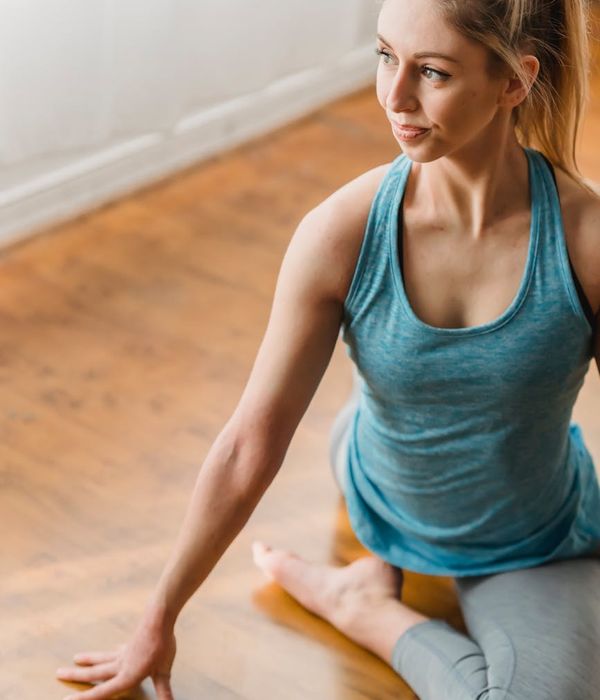 Happy woman in comfortable activewear stretching indoors.
